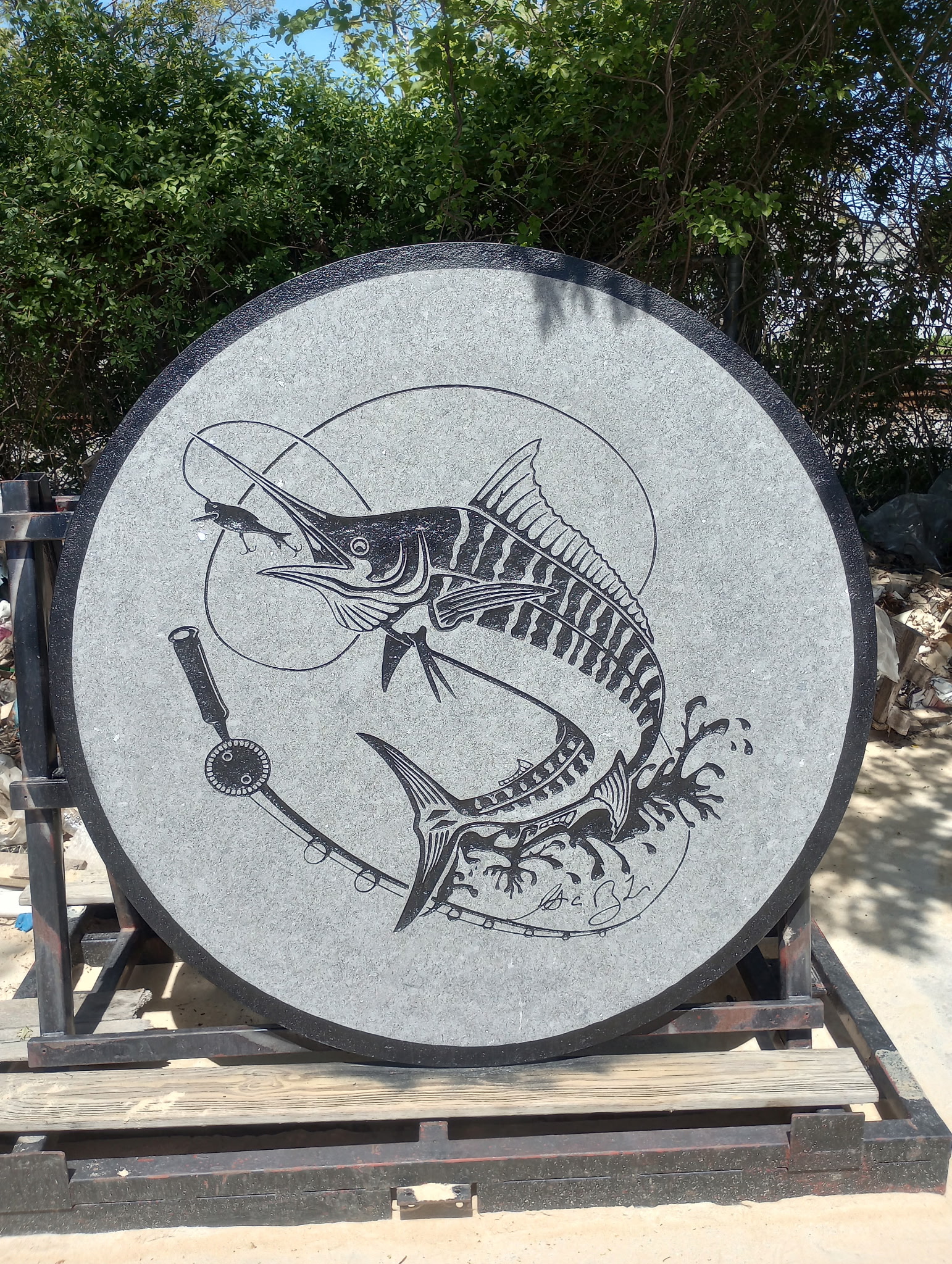 Custom carved granite medallion featuring a marlin and fishing rod design