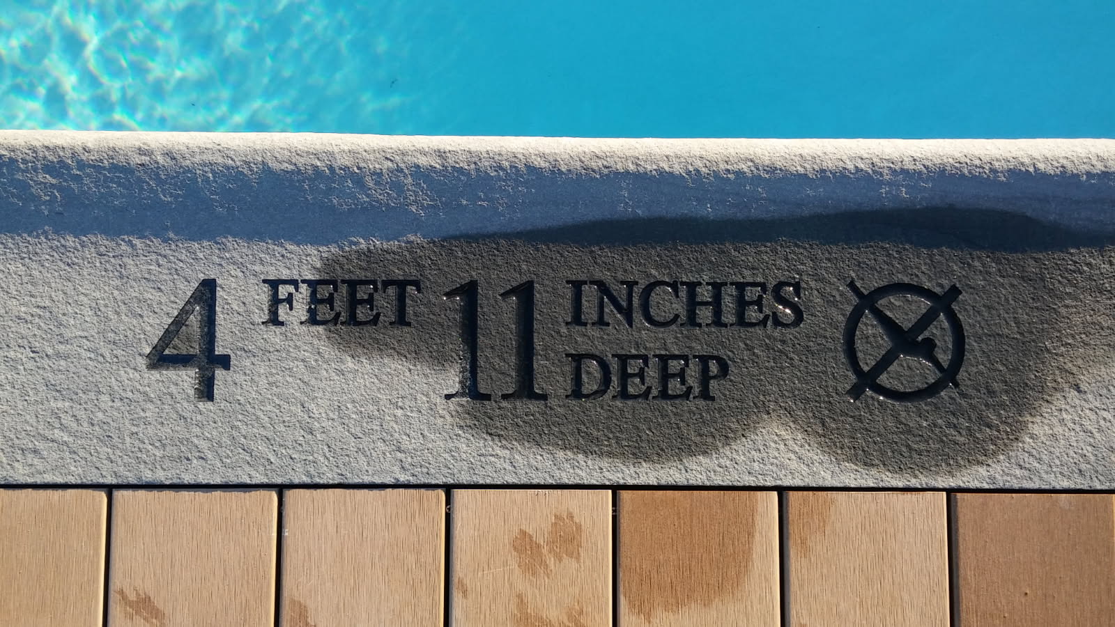 Engraved pool depth marker in stone coping