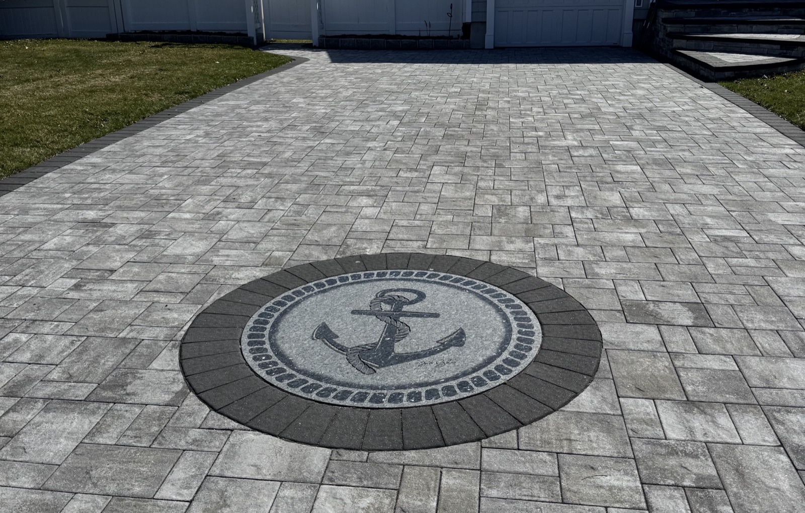 Anchor and rope medallion stone inlay on a paver driveway