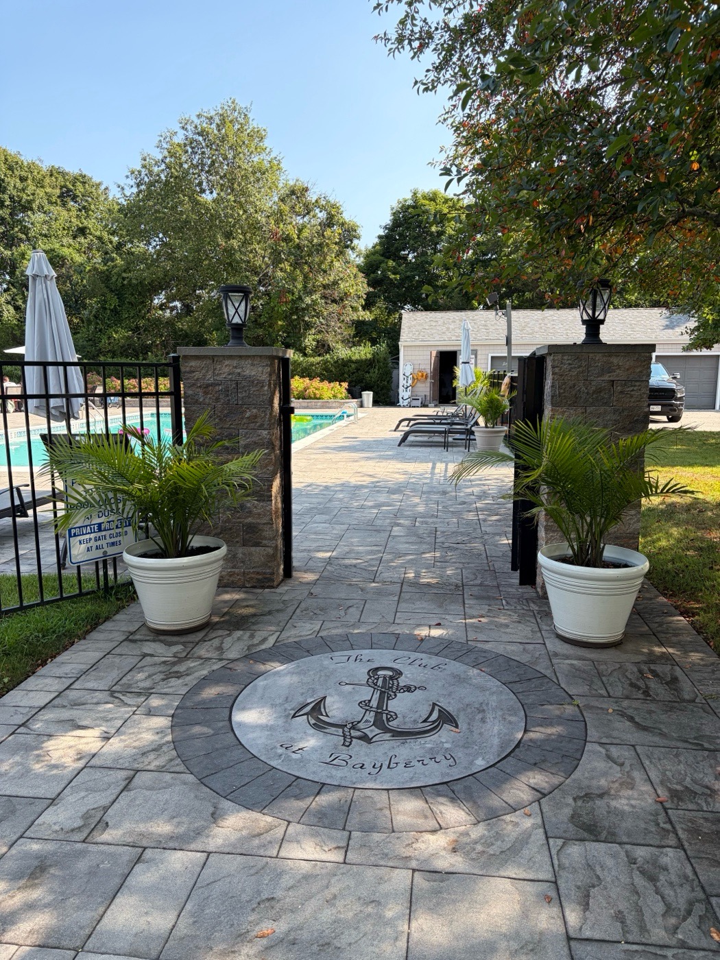 The Club at Bayberry anchor medallion inlay set into the stone walkway at a pool entrance