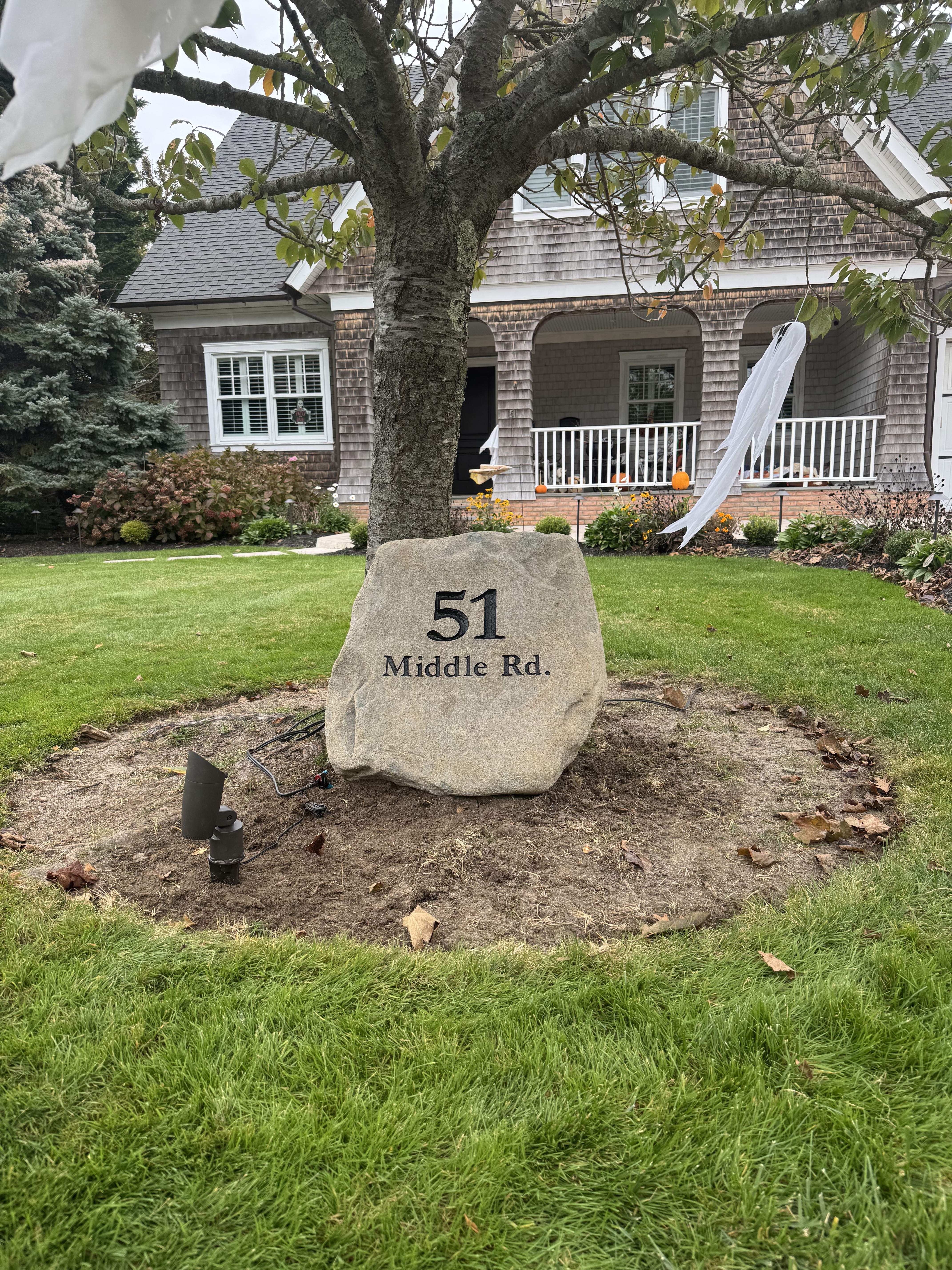 Engraved address rock reading 51 Middle Rd under a front yard tree