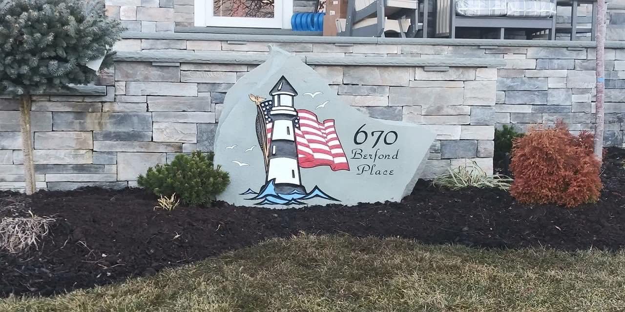 Engraved address rock reading 670 Berfond Place with a lighthouse and American flag design