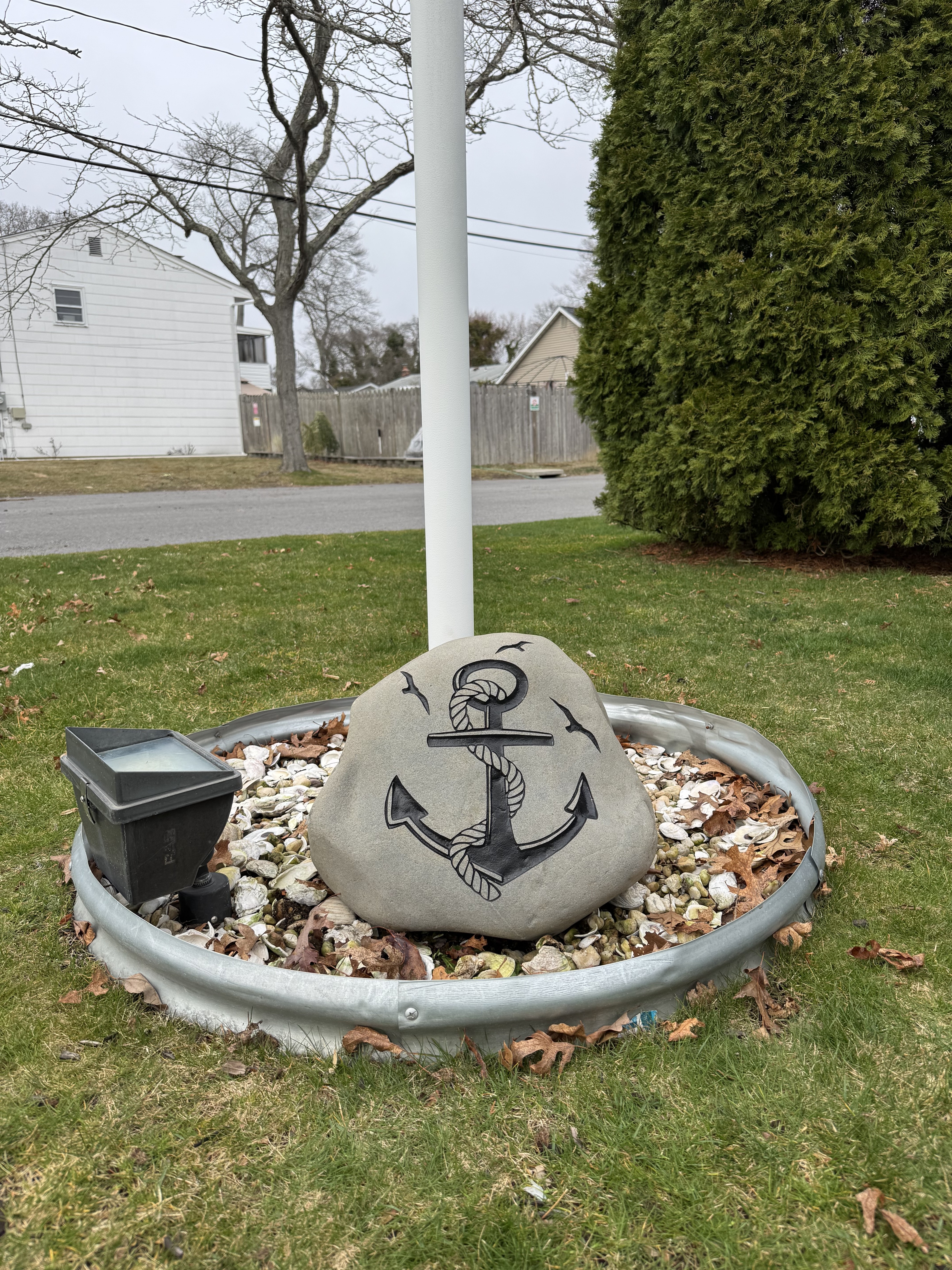 Engraved anchor and rope rock beside a flagpole