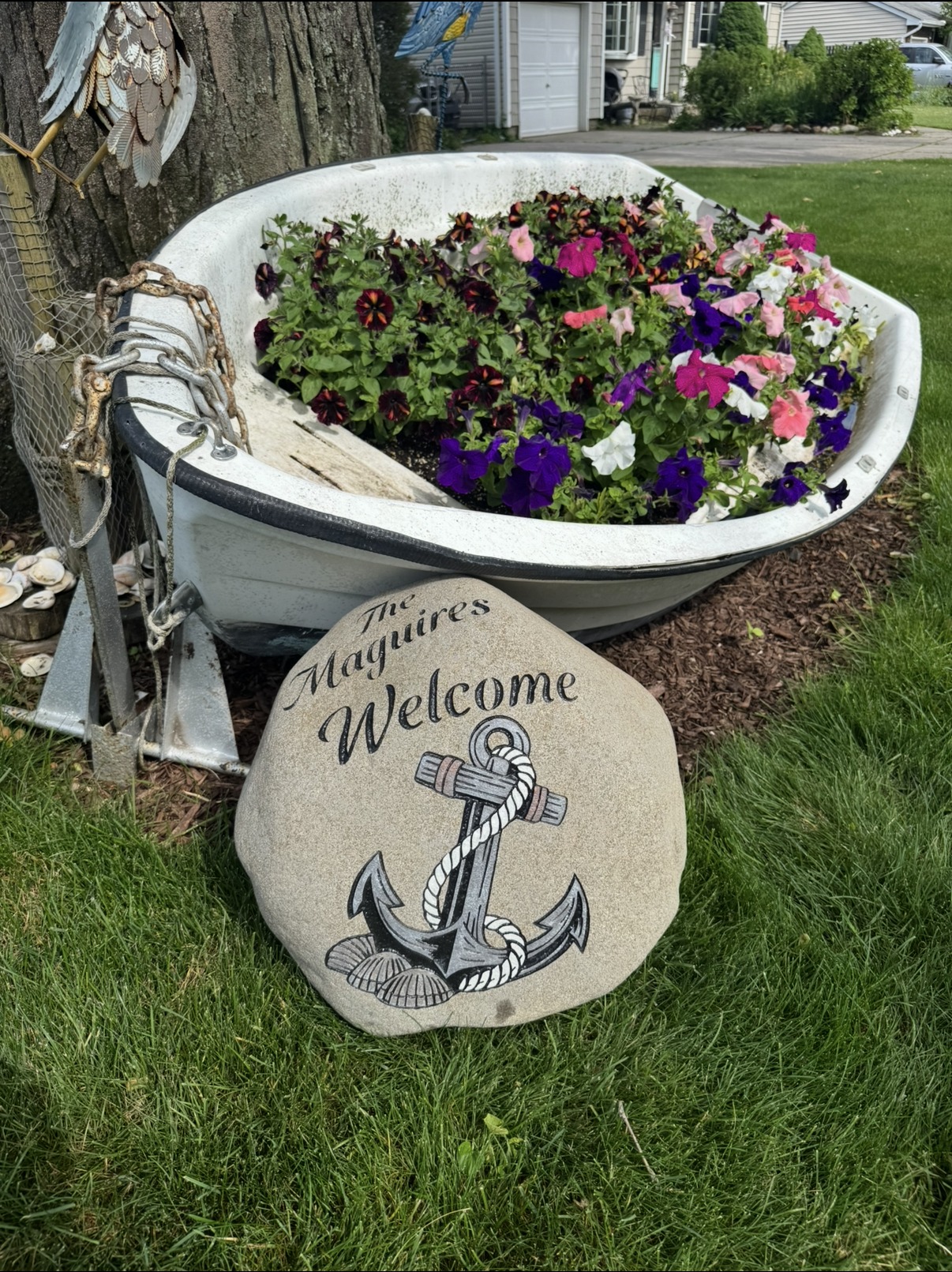 The Maguires Welcome anchor engraved rock beside a bathtub flower planter