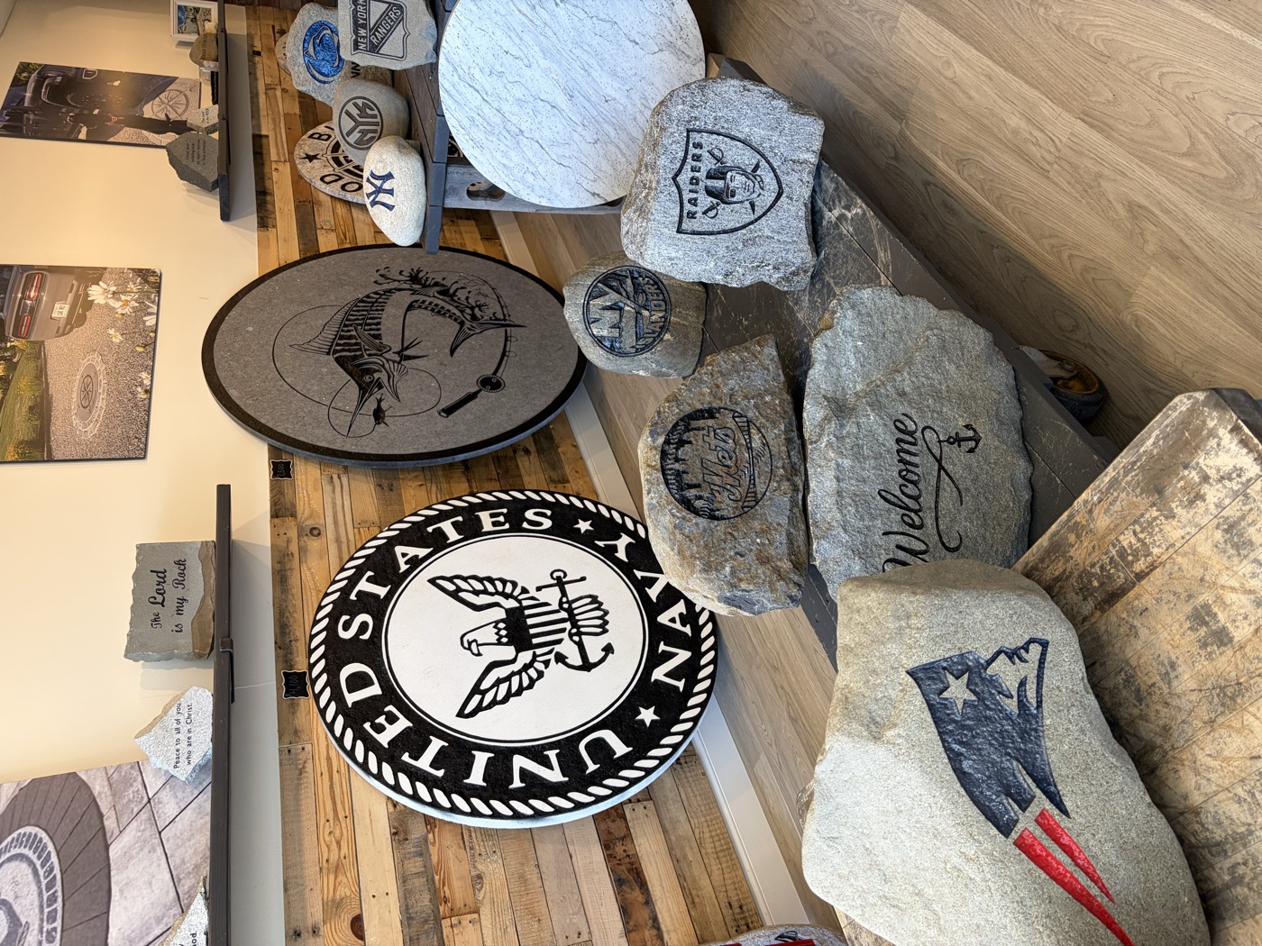 Showroom display of engraved rocks and stone medallions including US Navy, Patriots, Raiders and Jets designs