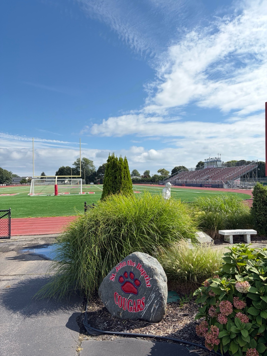 St. John the Baptist Cougars engraved rock with a red paw print, beside the school athletic field