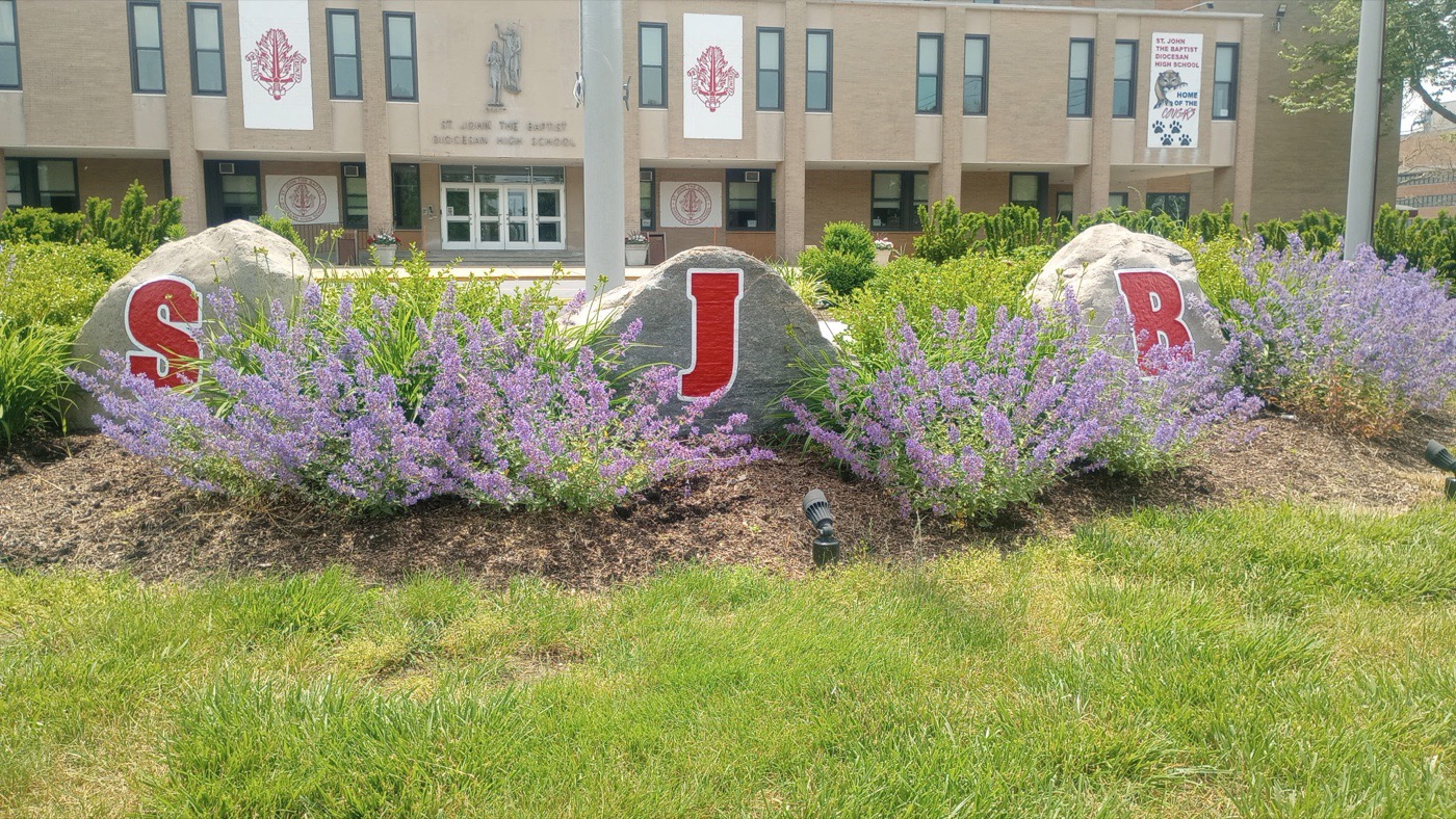 Three engraved boulders spelling S J B at the entrance to St. John the Baptist Diocesan High School