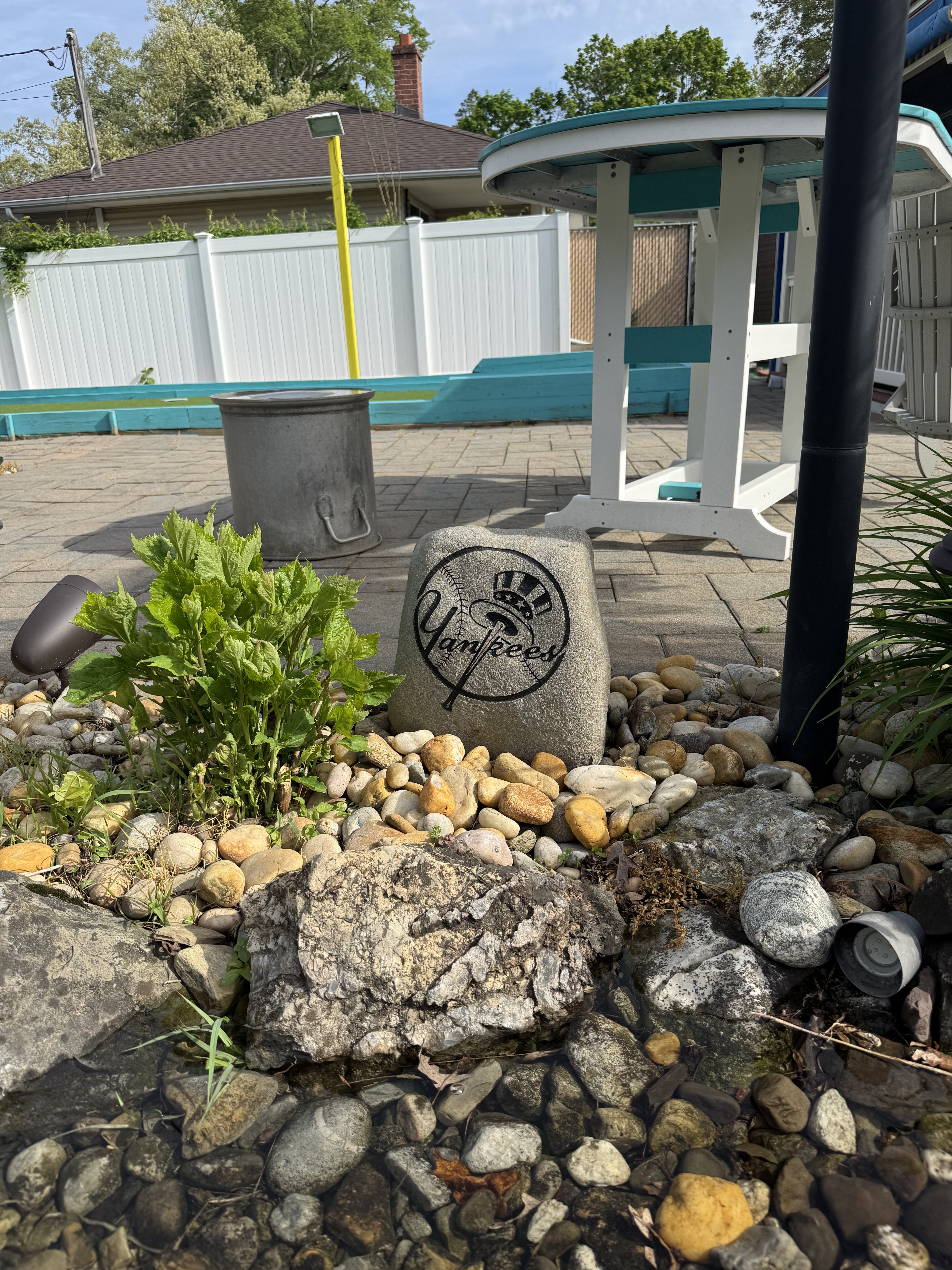 New York Yankees top hat logo engraved rock beside a poolside patio